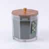 The Bridgewater Candle Company Festive Frasier Holiday Large Decorative Candle features soy-blend wax in a clear hexagonal jar with a wooden lid, gold knob, and green plaid tag tied with gold string. Background is white.