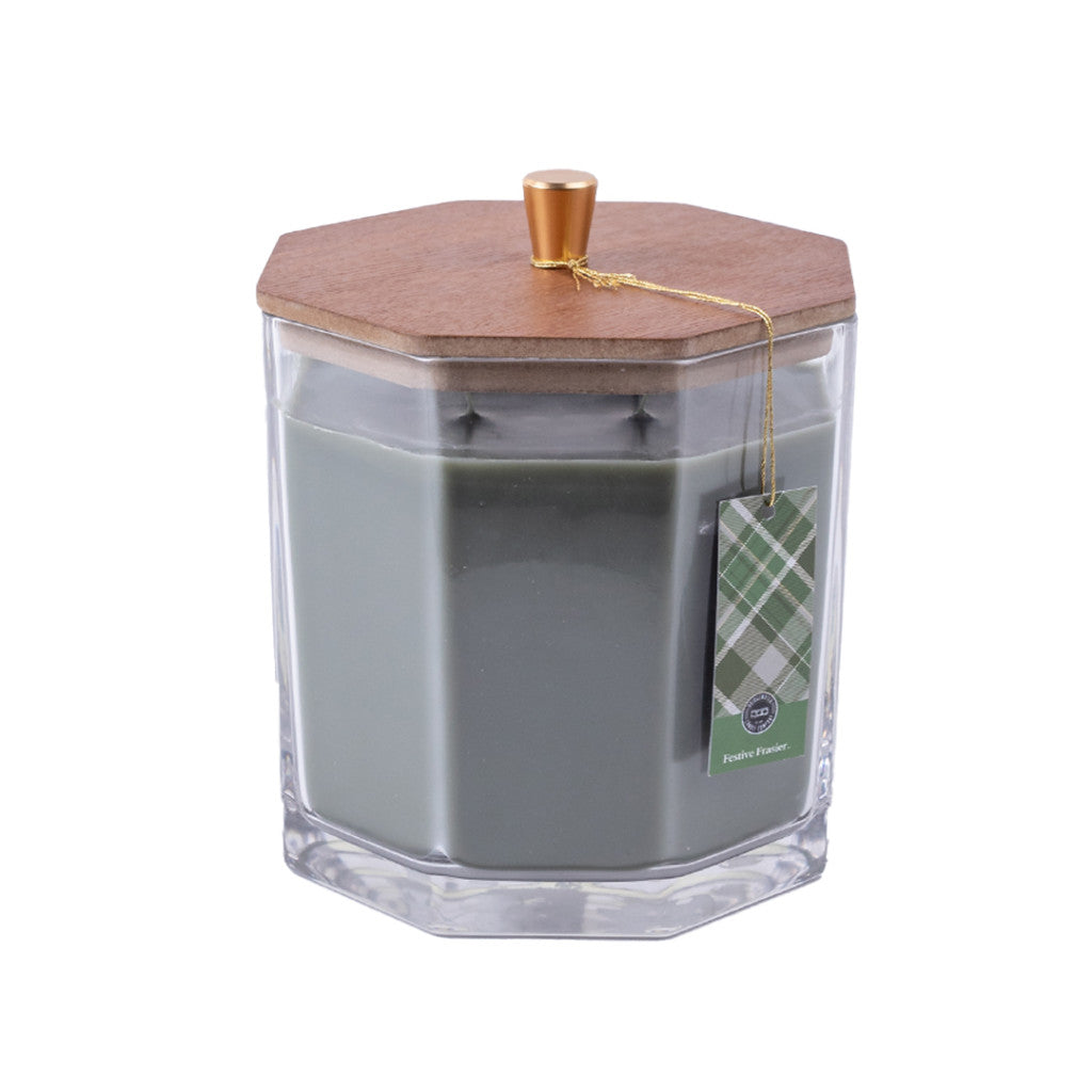 The Bridgewater Candle Company Festive Frasier Holiday Large Decorative Candle features soy-blend wax in a clear hexagonal glass jar with a wooden lid, gold knob, and green plaid tag, set against a plain white background.