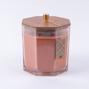 The Bridgewater Candle Company Harvest Pumpkin Holiday Large Decorative Candle features orange soy-blend wax in a hexagonal glass jar with a wooden lid and gold knob, plus a plaid tag reading "Harvest Pumpkin," all set against a plain white background.