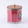The Christmas Bliss Holiday Large Decorative Candle by Bridgewater Candle Company features pink soy-blend wax in a clear hexagonal jar with wooden lid, gold knob, and a festive plaid tag.