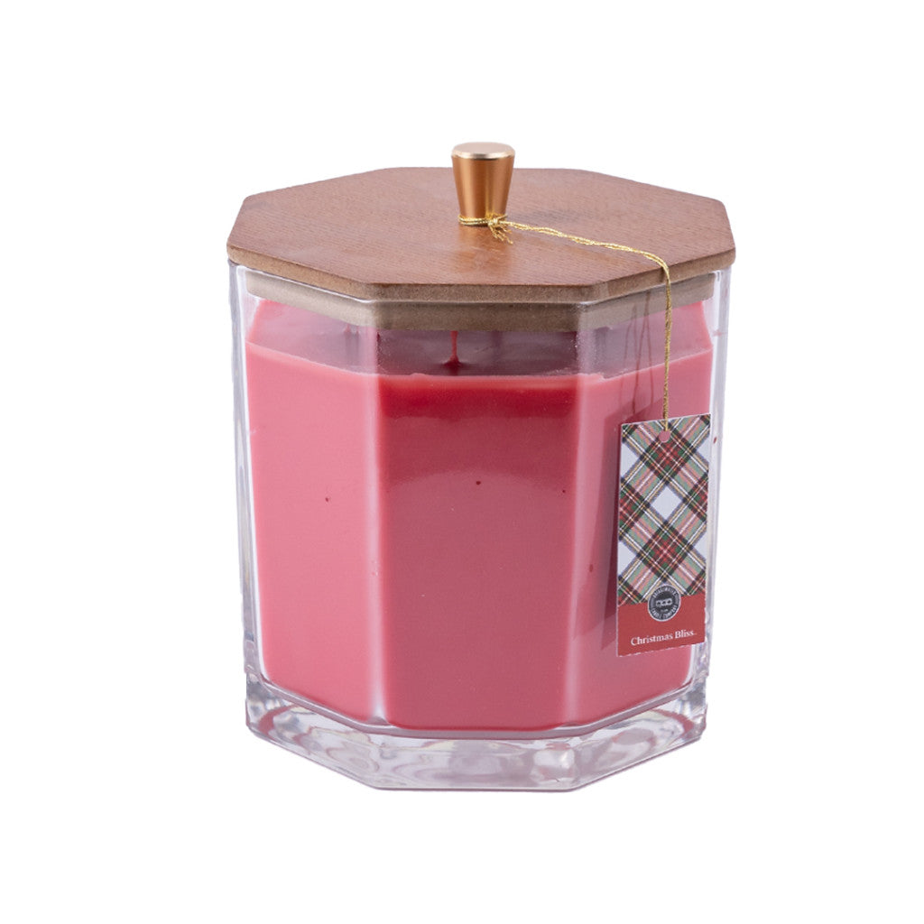 The Bridgewater Candle Company Christmas Bliss Holiday Large Decorative Candle features pink soy-blend wax in a clear faceted jar with a wood hex lid, gold pull tab, and plaid Christmas Bliss tag—ideal for festive décor.