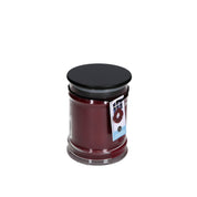 The Bridgewater Candle Company’s Welcome Home 8oz Jar Candle is a dark red, soy-blend candle with a black lid and a blue label featuring a wreath design, shown against a white background.
