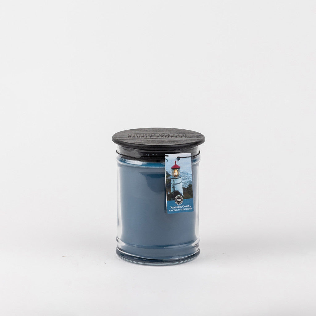 The Bridgewater Candle Company Nantucket Coast 8oz Jar Candle sits in clear glass with a black lid and lighthouse tag, evoking coastal serenity—all photographed on a plain white background.