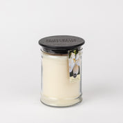 The Bridgewater Candle Company Sweet Magnolia 18oz Large Jar Candle features ivory wax, a black wooden lid, and a tag with a white flower image and Sweet Magnolia text. The candle is set against a plain white background.