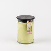 The Spring Dress 18oz Large Jar Candle by Bridgewater Candle Company features pale yellow wax, a black lid, and a label with a white duck and pink text. This floral candle stands out against a plain white background.