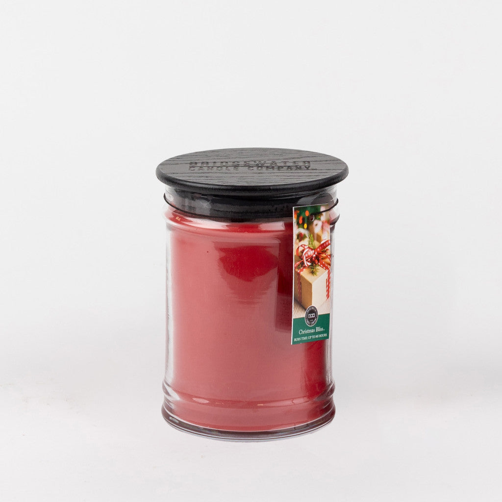 The Bridgewater Candle Company Christmas Bliss 18oz Large Jar is a red candle with a black lid and a label featuring a decorated cake and the text Christmas Bliss, set against a plain white background.
