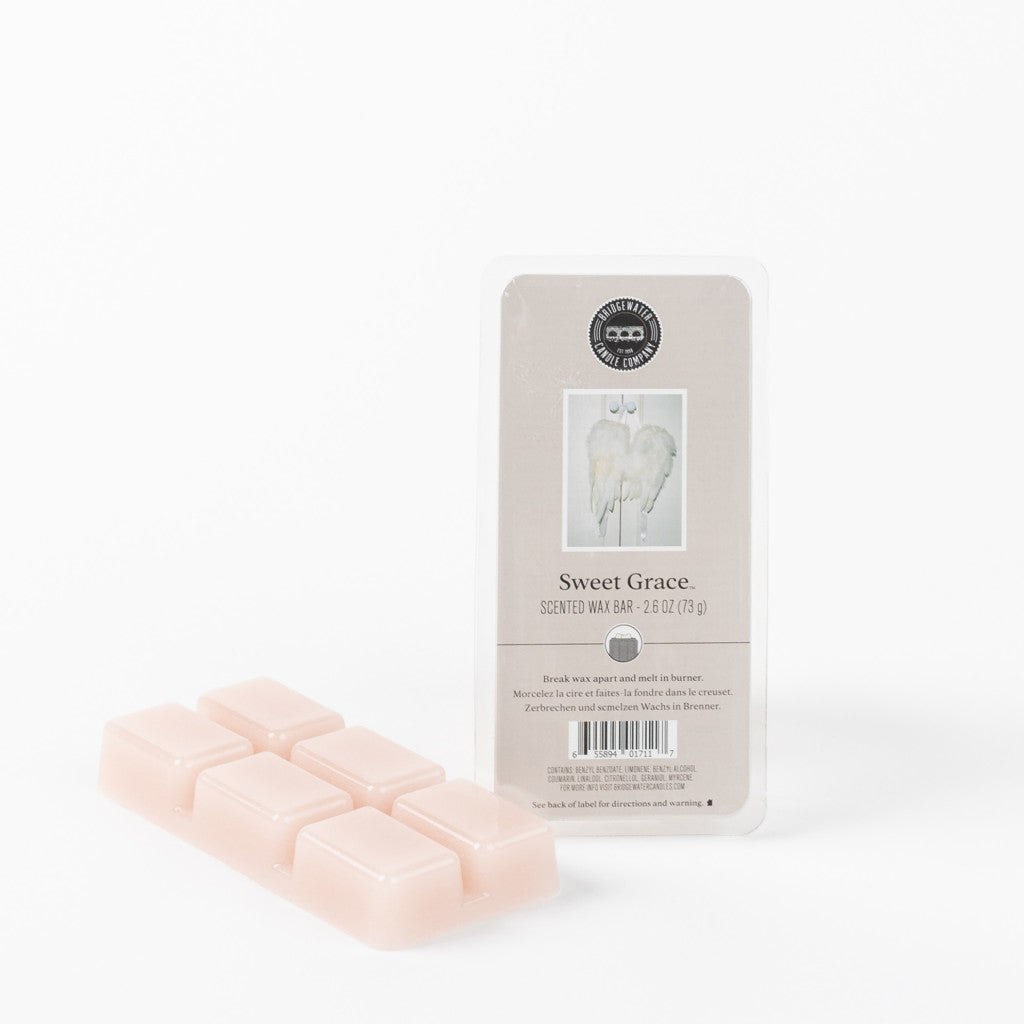 A pack of six light pink Sweet Grace Wax Bars by Bridgewater Candle Company sits beside its angel-wing packaging labeled Sweet Grace Scented Wax Bar. Enjoy flameless fragrance with these soy-blend wax melts against a white backdrop.