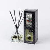A Bridgewater Candle Company Afternoon Retreat Reed Diffuser with black fiber reeds sits next to its box, which displays a nature scene and branding. The diffuser holds a light-hued premium fragrance.