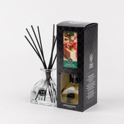 The Bridgewater Candle Company Christmas Bliss Reed Diffuser, with black reeds and festive packaging, sits against a dark, patterned backdrop—an ideal accent to elevate your seasonal décor.