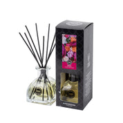 The Bridgewater Candle Company XOXO Reed Diffuser with black fiber reeds stands next to its stylish box, adorned with a floral design and the label Reed Diffuser. The premium diffuser contains a pale yellow fragrance liquid.