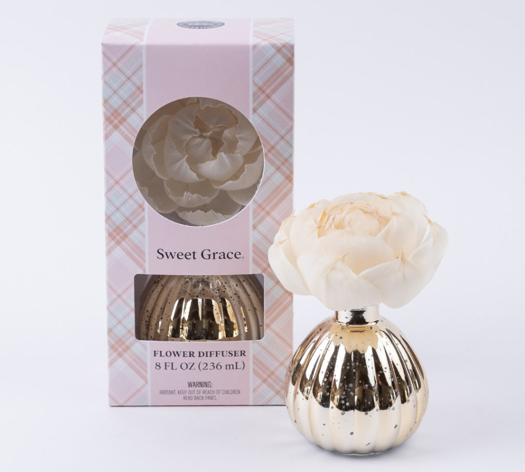 The Bridgewater Candle Company Sweet Grace Mercury Flower Diffuser features an ivory faux flower in a gold ribbed vase, paired with pink plaid packaging with a circular window—an elegant addition to your home fragrance décor.