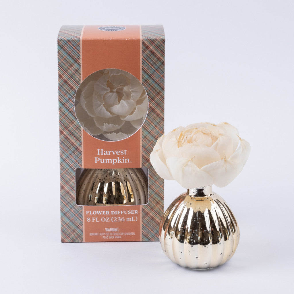 A gold-striped Harvest Pumpkin Mercury Flower Diffuser from Bridgewater Candle Company, featuring a white flower, is displayed beside its plaid box with a window that reveals the diffuser. The packaging is labeled “Harvest Pumpkin” and the diffuser fills your space with a cozy pumpkin spice scent.