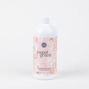 A white plastic bottle of Bridgewater Candle Company’s Sweet Grace 32oz Laundry Detergent, with a pink label featuring bubbles. The label shows product name and size (32 fl oz/946 mL). Enjoy a luxurious, long-lasting scent. Background is plain white.