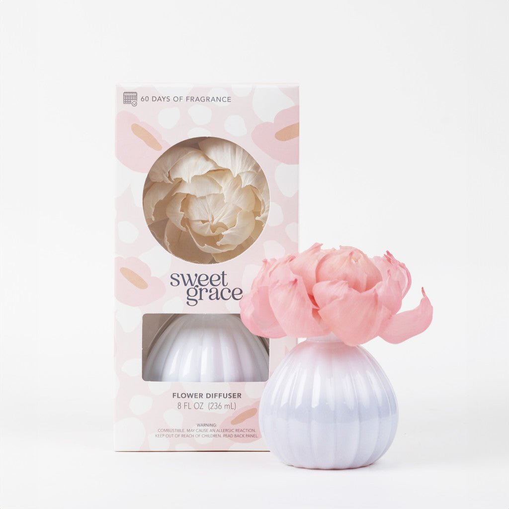 The Bridgewater Candle Company Sweet Grace Flower Diffuser, featuring pink petals in a white rounded vase, is displayed beside its box packaging with a cut-out window and Sweet Grace branding, beautifully showcasing the diffuser inside.