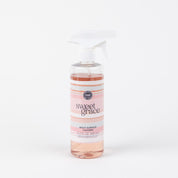 A clear spray bottle of Bridgewater Candle Companys Sweet Grace Multi-Surface Cleaner with pink liquid, a white spray nozzle, and a light pink label is displayed against a plain white background.