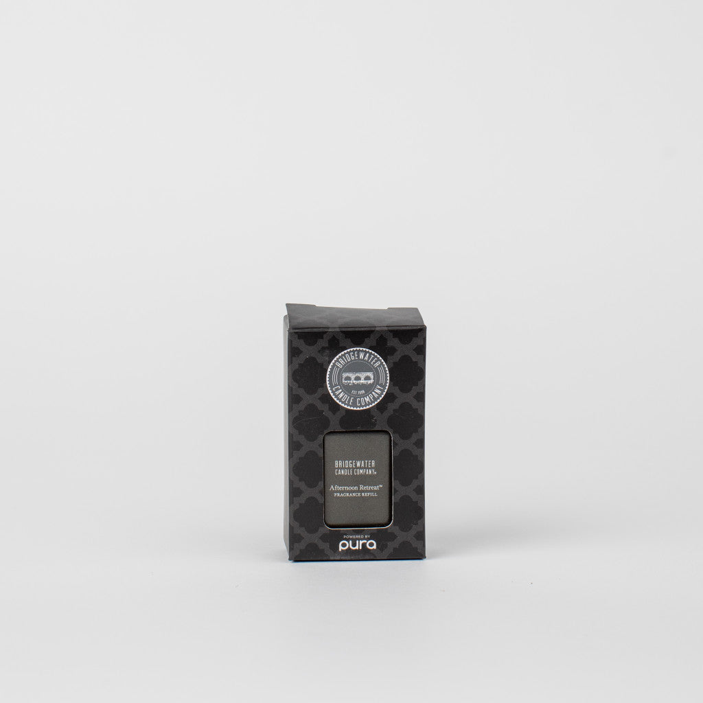 A black box of Pura + Bridgewater Fragrance Refill - Afternoon Retreat by Bridgewater Candle Company sits centered on a white background. The packaging shows a subtle pattern, brand name, and fragrance title.