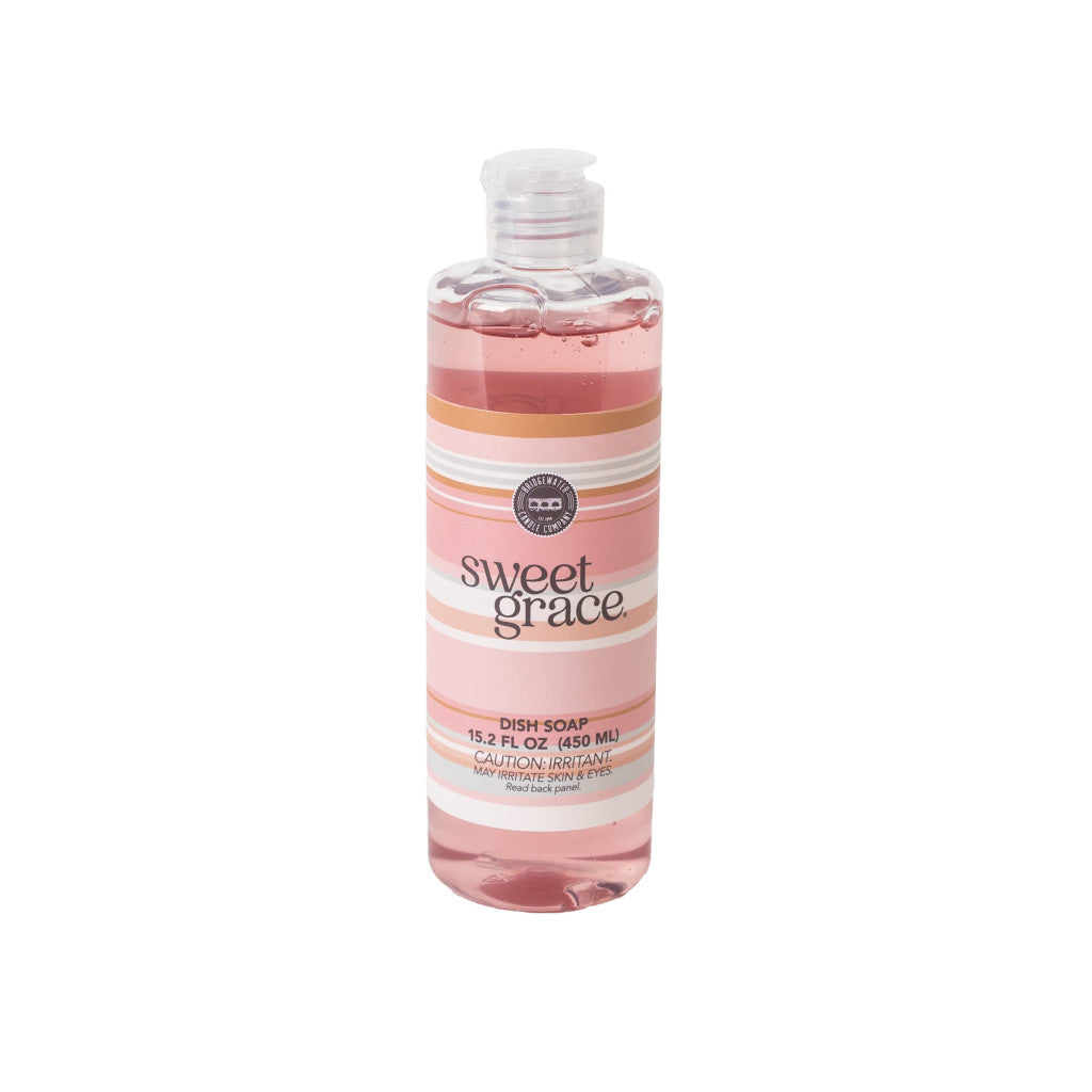 Bridgewater Candle Company’s Sweet Grace Dish Soap comes in a clear 15.25 fl oz (450 ml) bottle with pink liquid, a white flip-top cap, and a striped pink, peach, and white label—enjoy their best-selling scent in every wash.