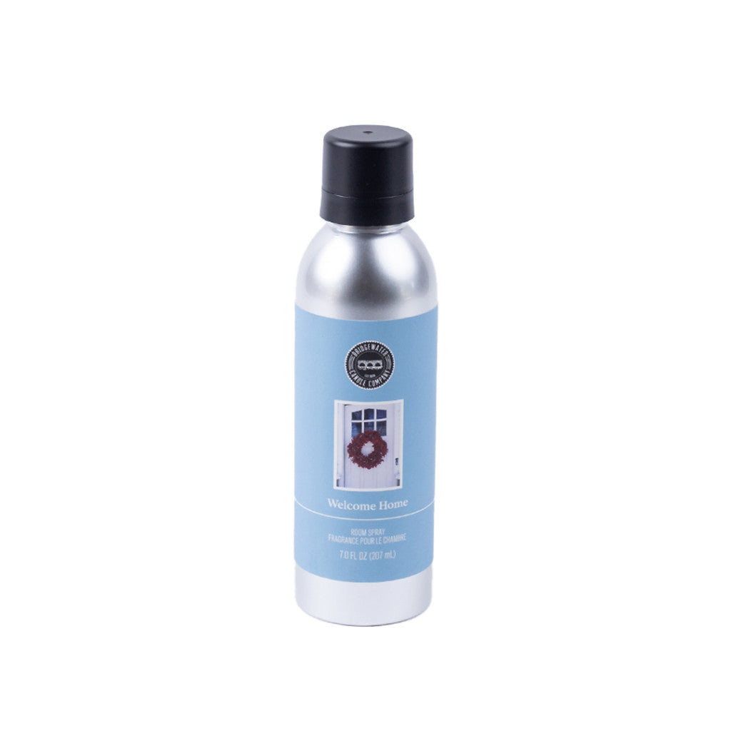 A silver can with black cap and blue label reading Welcome Home and Room Spray, featuring a wreath on a door. Add inviting fragrance to your space with Bridgewater Candle Companys Welcome Home Non-Aerosol Room Spray.