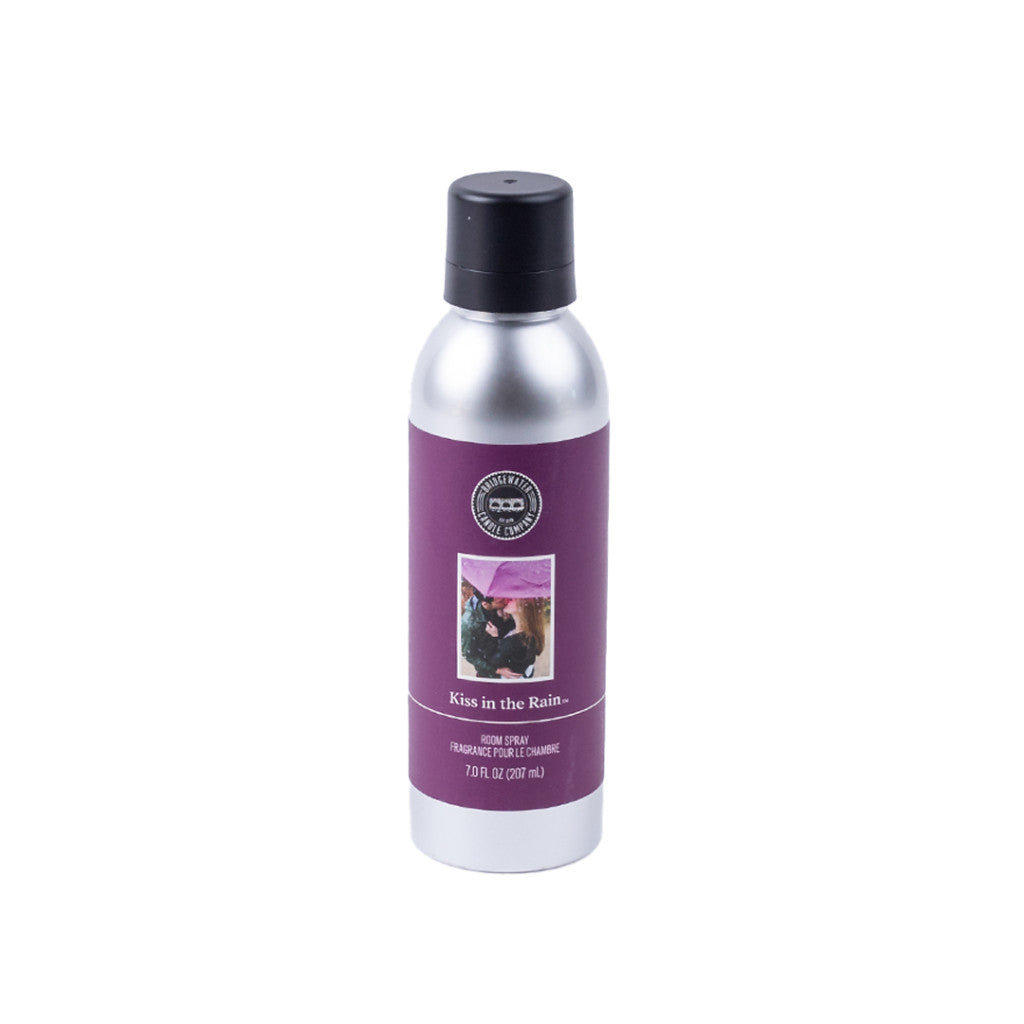Enjoy a romantic atmosphere with Bridgewater Candle Companys Kiss in the Rain Non-Aerosol Room Spray, 7 oz silver bottle with black cap and purple label featuring two people kissing under an umbrella.