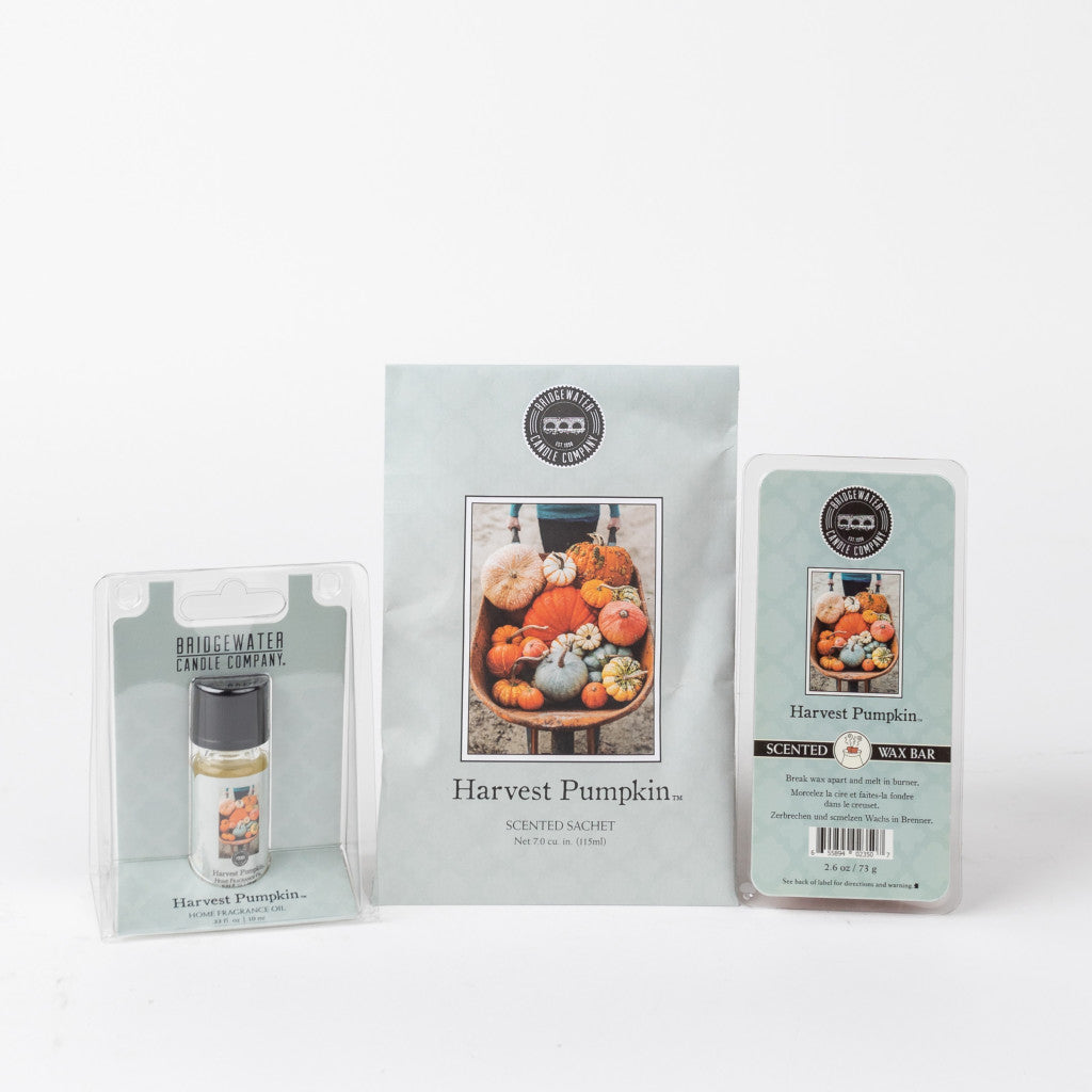 The Bridgewater Candle Company Harvest Pumpkin Flameless Bundle includes a small bottle, sachet, and wax bar with assorted pumpkin designs on white labels, delivering cozy pumpkin spice vibes.
