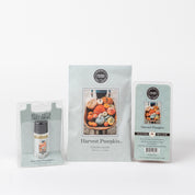 The Bridgewater Candle Company Harvest Pumpkin Flameless Bundle includes a small bottle, sachet, and wax bar with assorted pumpkin designs on white labels, delivering cozy pumpkin spice vibes.
