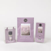 The Bridgewater Candle Company’s Lavender Fields Flameless Bundle displays a scented sachet, wax melt, and fragrance oil in lavender packaging with lavender flower imagery for effortless home fragrance.