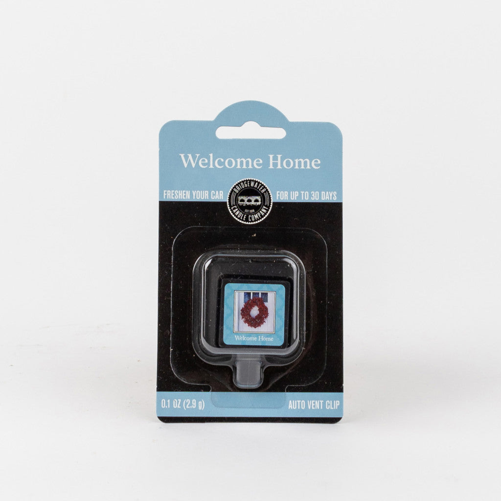 The Bridgewater Candle Company Welcome Home Auto Vent Clip is a black-packaged car air freshener with a blue top, lasting up to 30 days. The vent clip features a blue label and red floral design for long-lasting fragrance in your car.