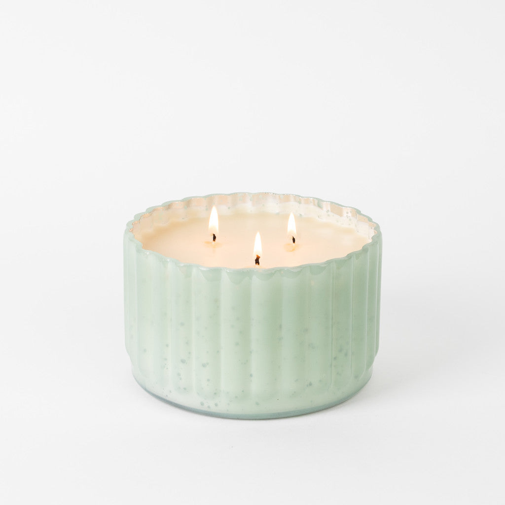A light green, ribbed ceramic container holds the Bridgewater Candle Company Sweet Grace Collection Candle #065 with soy-blend wax, its three flames glowing brightly against a plain white background.