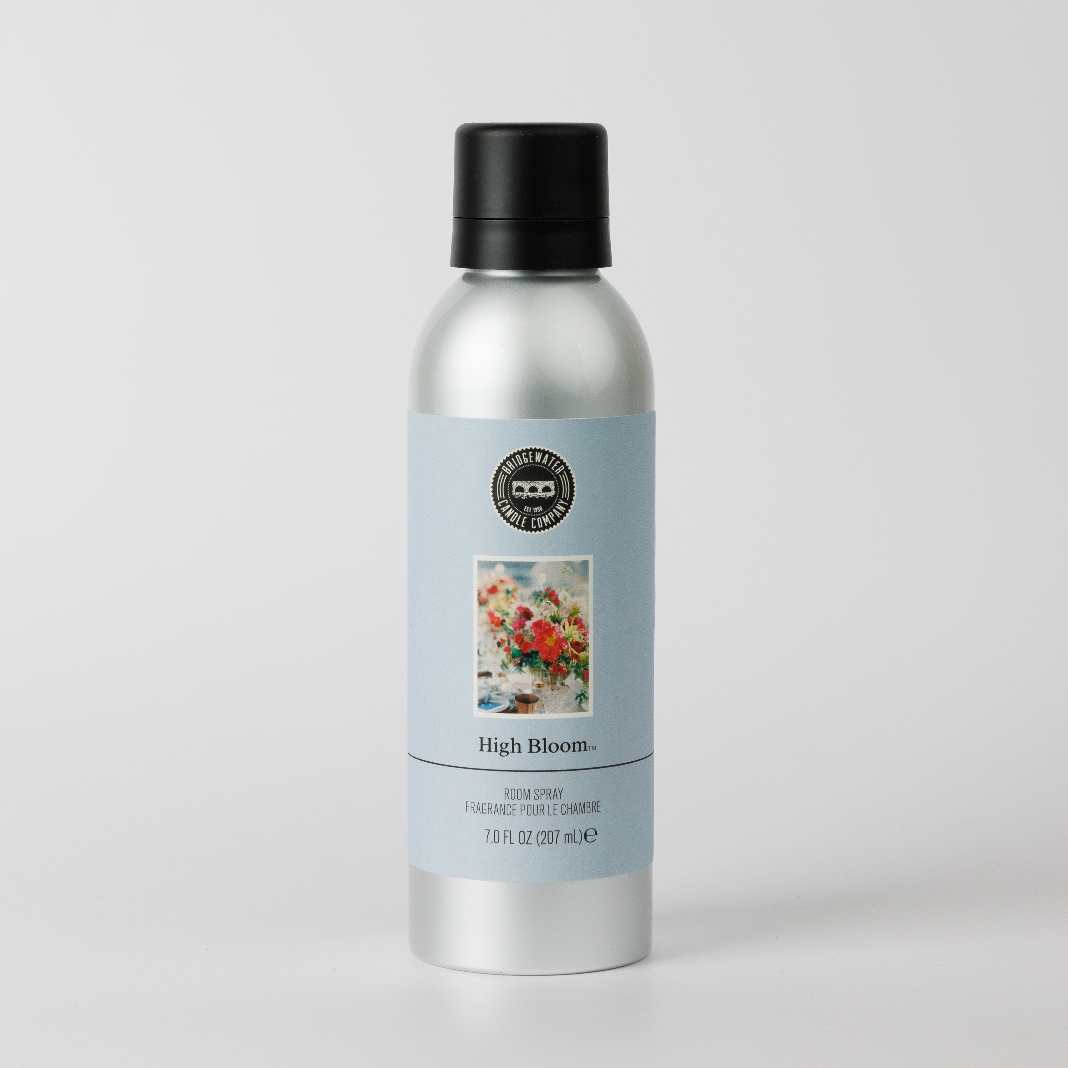 A silver spray bottle with a black cap and light blue label shows a floral image and the words “High Bloom Non-Aerosol Spray, Bridgewater Candle, 7.0 fl oz (207 ml)” on a plain white background.