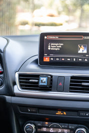 A small square Bridgewater Auto Vent Clip-Nantucket Coast air freshener clipped to the center dashboard vent of a car.