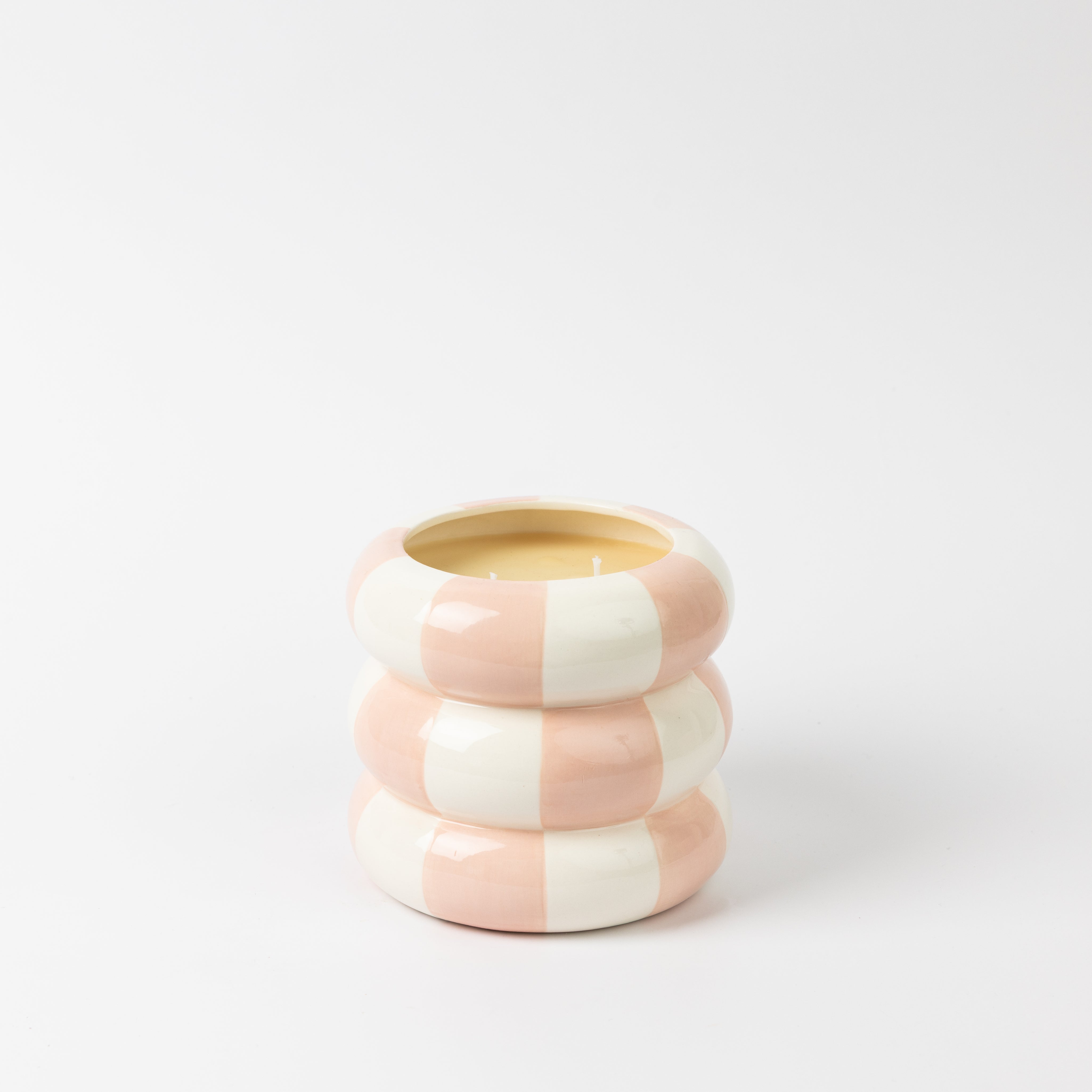 A round, stacked ceramic candle holder with wide pink and white stripes holds the Bridgewater Candle Sweet Grace Collection Candle #074, a soy-blend candle, displayed against a plain white background.