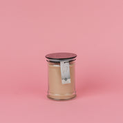 A beige Bridgewater Candle Sweet Grace 18oz Large Jar Candle with a dark lid sits on a pink background. An angel wings label hangs from the lid, highlighting the signature Sweet Grace fragrance.