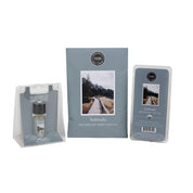 The Bridgewater Candle Solitude Flameless Bundle includes a home fragrance oil, a scented sachet with a nature scene, and a wax bar—all with matching blue-gray minimalist labels for a soothing ambiance.