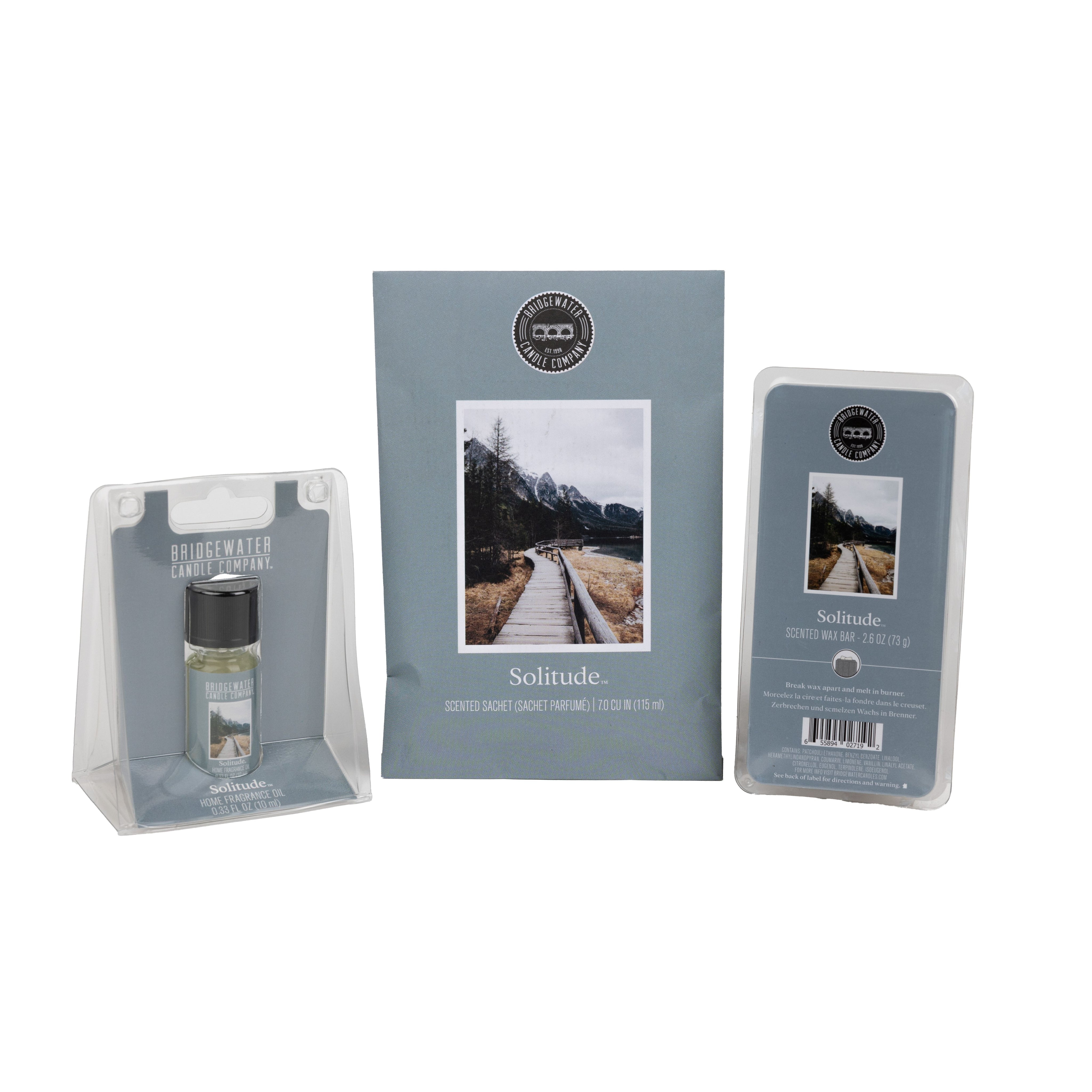 The Bridgewater Candle Solitude Flameless Bundle includes a home fragrance oil, a scented sachet with a nature scene, and a wax bar—all with matching blue-gray minimalist labels for a soothing ambiance.