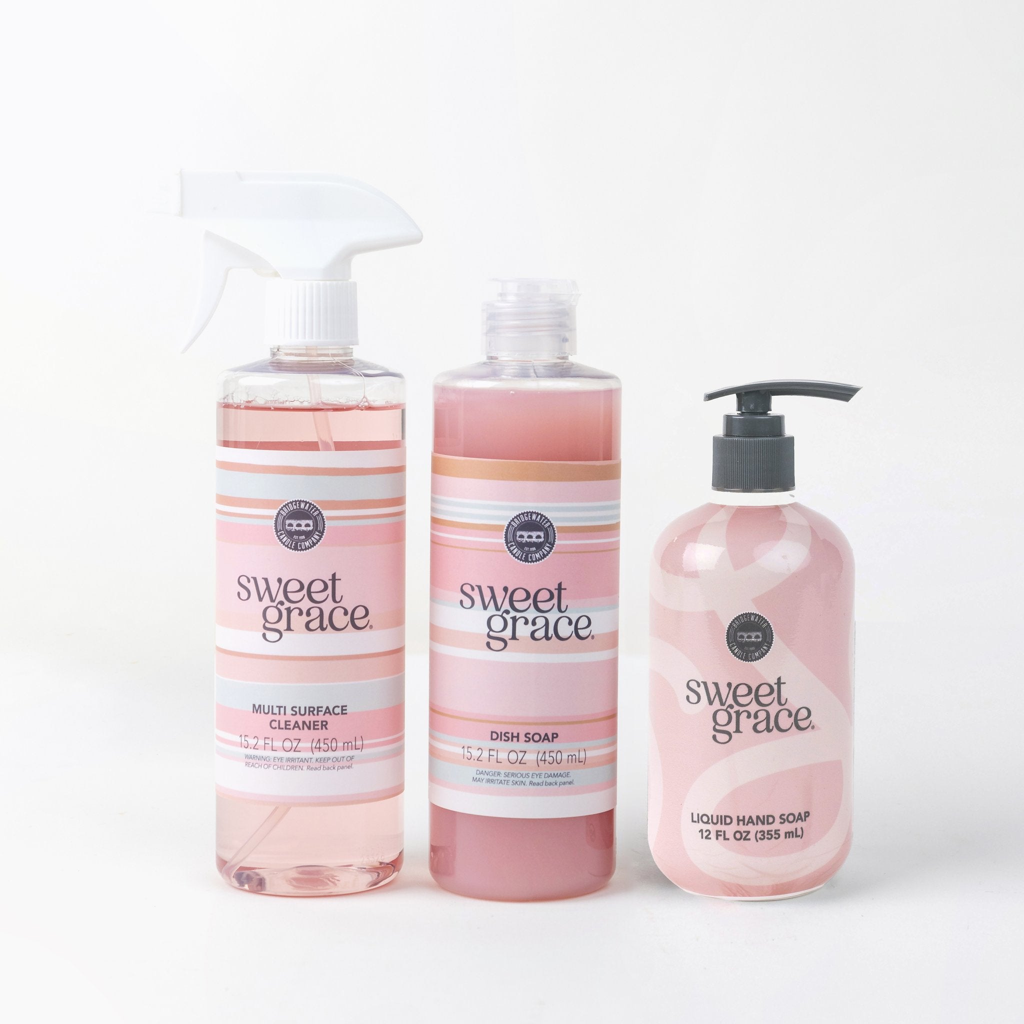 The Sweet Grace Scrub & Cleanse Bundle features a Multi Surface Spray, dish soap, and hand soap in pink bottles, displayed together against a white background to add elegance and fragrance to your cleaning routine.