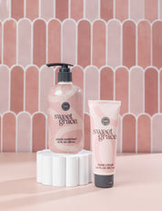 The Sweet Grace On Hand Bundle by Fast Bundle, featuring Hand Cream and Liquid Hand Soap, is displayed on a white pedestal with a pink tiled background—an ideal duo to elevate your handcare routine.