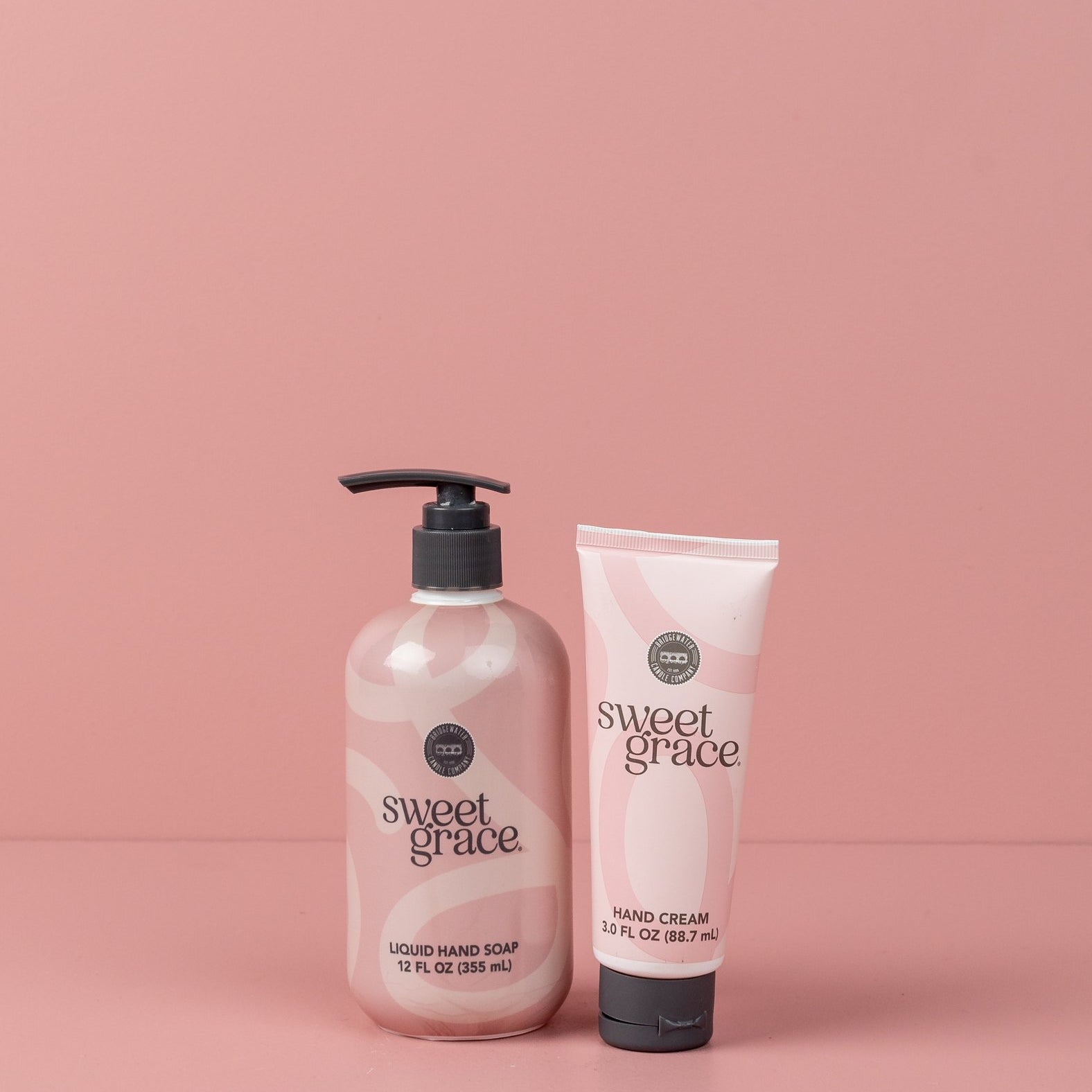 The Sweet Grace On Hand Bundle—featuring Hand Cream and Liquid Hand Soap—stands side by side on a light pink surface with a matching background, perfect for elevating your handcare routine.