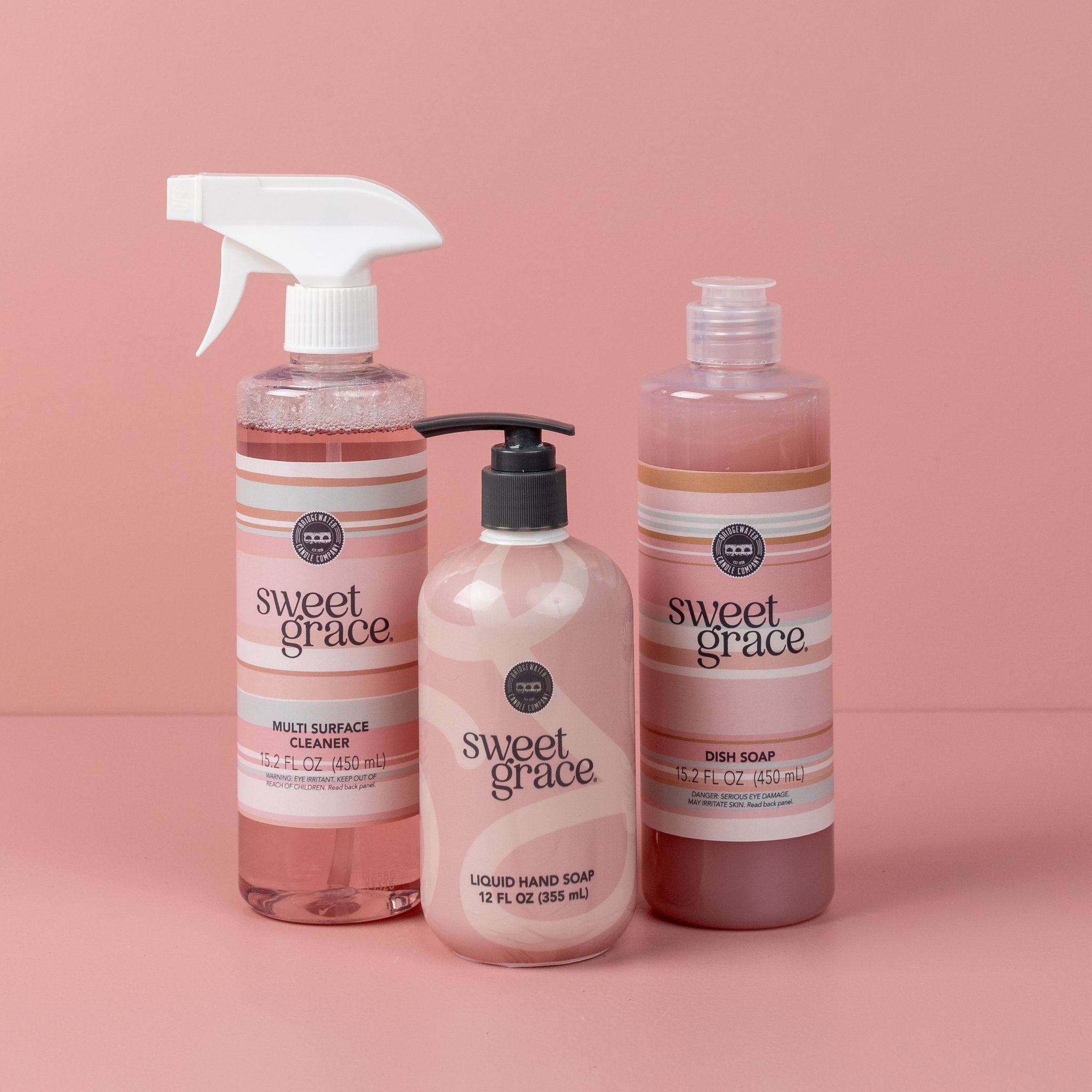 The Sweet Grace Scrub & Cleanse Bundle features three pink-toned products—Multi-Surface Spray, liquid hand soap with a pump, and dish soap—displayed against a pink background.