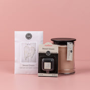 The Sweet Grace Starter Bundle, featuring a scented sachet, an auto vent clip, and a candle in a glass jar, is elegantly displayed against a soft pink background.