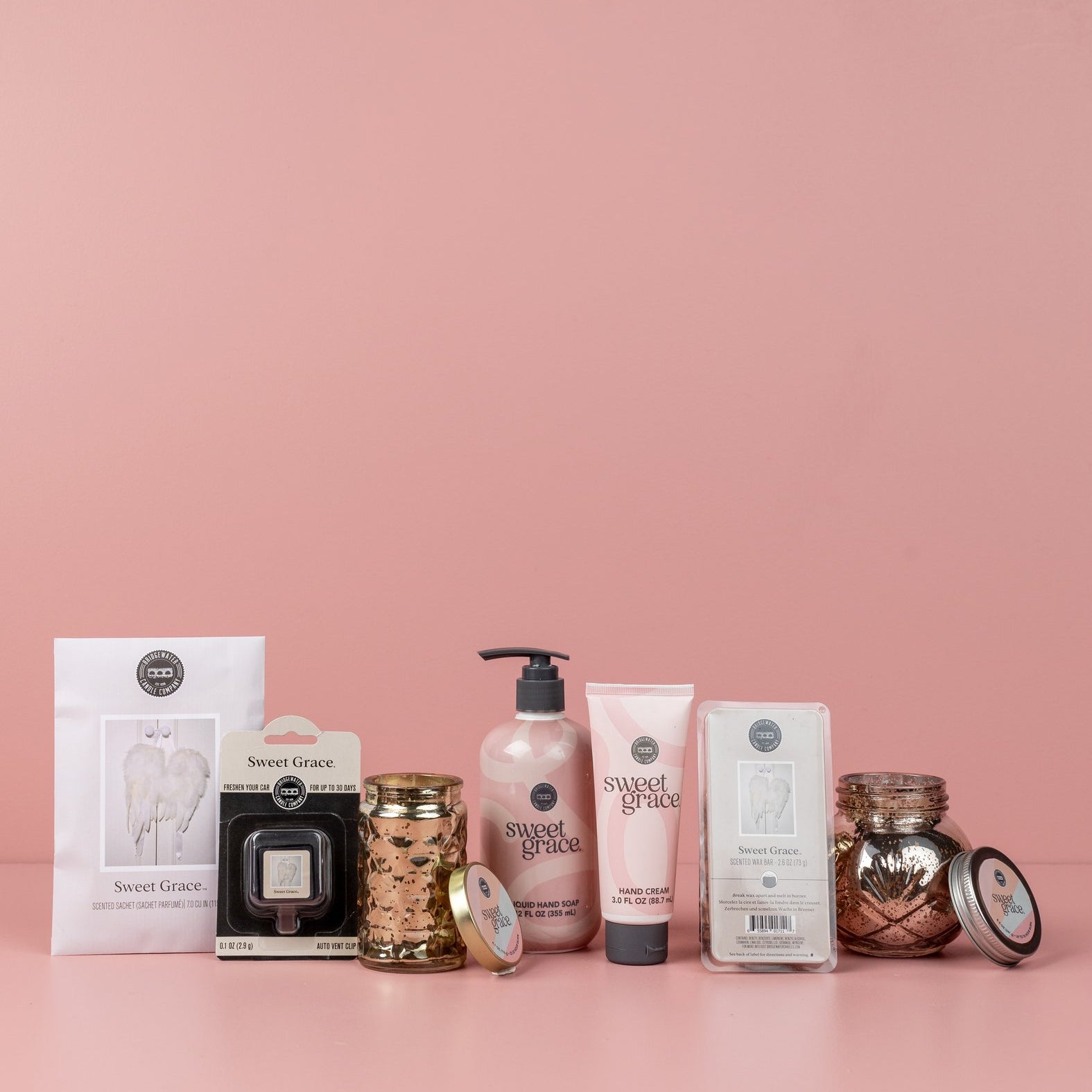 The Sweet Grace Lucky 7 Bundle features lotion, candle, wax melts, hand cream, and air fresheners arranged in a row against a light pink background.