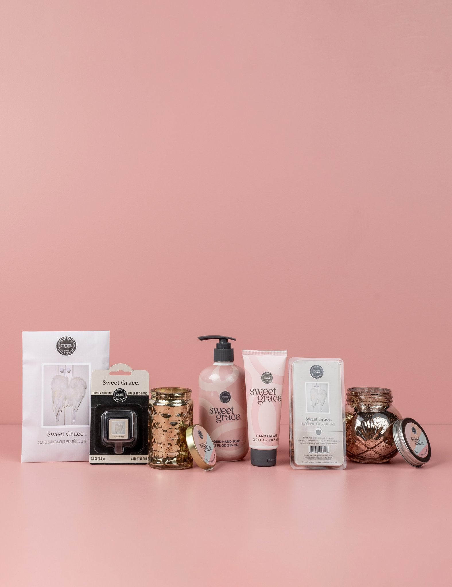 The Sweet Grace Lucky 7 Bundle features lotion, candle, wax melts, hand cream, and air fresheners arranged in a row against a light pink background.