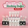 Sweet Grace Stocking Stuffer Bundle by Fast Bundle—lotions, hand creams, candles, and fragranced sachets—are displayed neatly on a pink background with a festive sign above, highlighting these perfect Holiday Gifts.