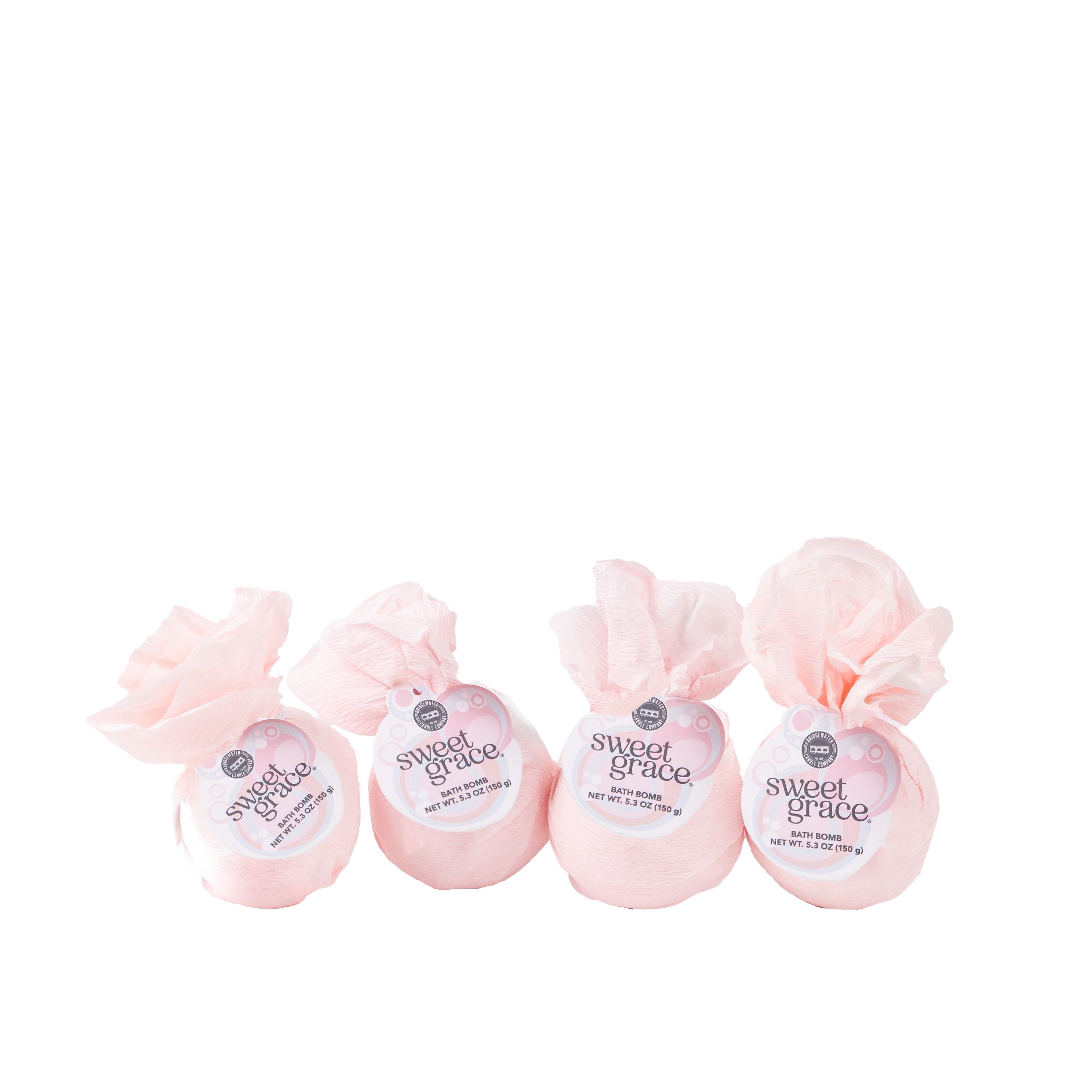 A set of four Sweet Grace bath bombs by Bridgewater Candle, wrapped in pink tissue and tied at the top, are beautifully arranged in a row against a white background.