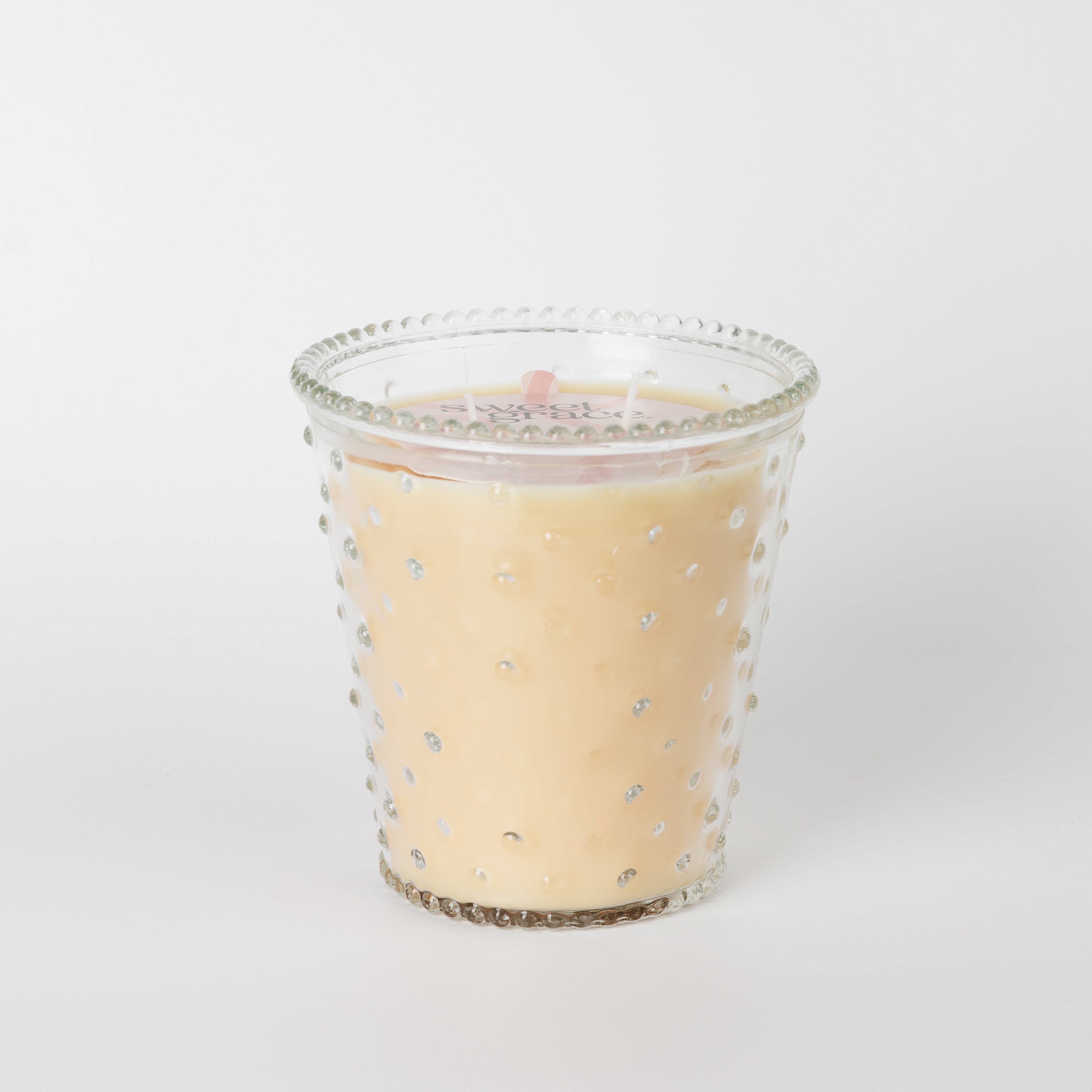 The Bridgewater Candle Sweet Grace Collection Candle #080 features a cream hue in a clear hobnail glass jar with raised dots, displayed against a plain white background.