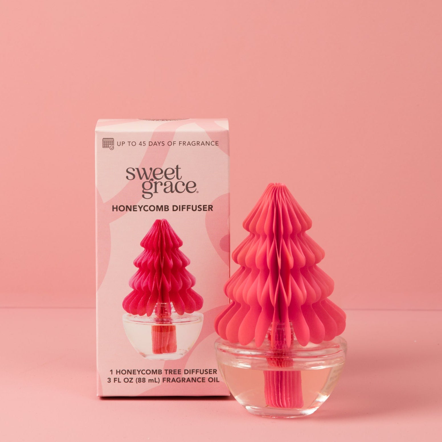 A pink honeycomb tree-shaped Sweet Grace Holiday Honeycomb Diffuser by Bridgewater Candle sits in front of its matching box, both labeled accordingly, against a pink background—the perfect gift for long-lasting fragrance.