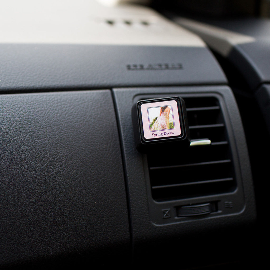 The Bridgewater Candle Company Spring Dress Auto Vent Clip fills your car with a light floral scent, featuring a chic design clipped to the dashboard.
