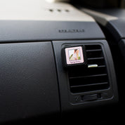 The Bridgewater Candle Company Spring Dress Auto Vent Clip fills your car with a light floral scent, featuring a chic design clipped to the dashboard.