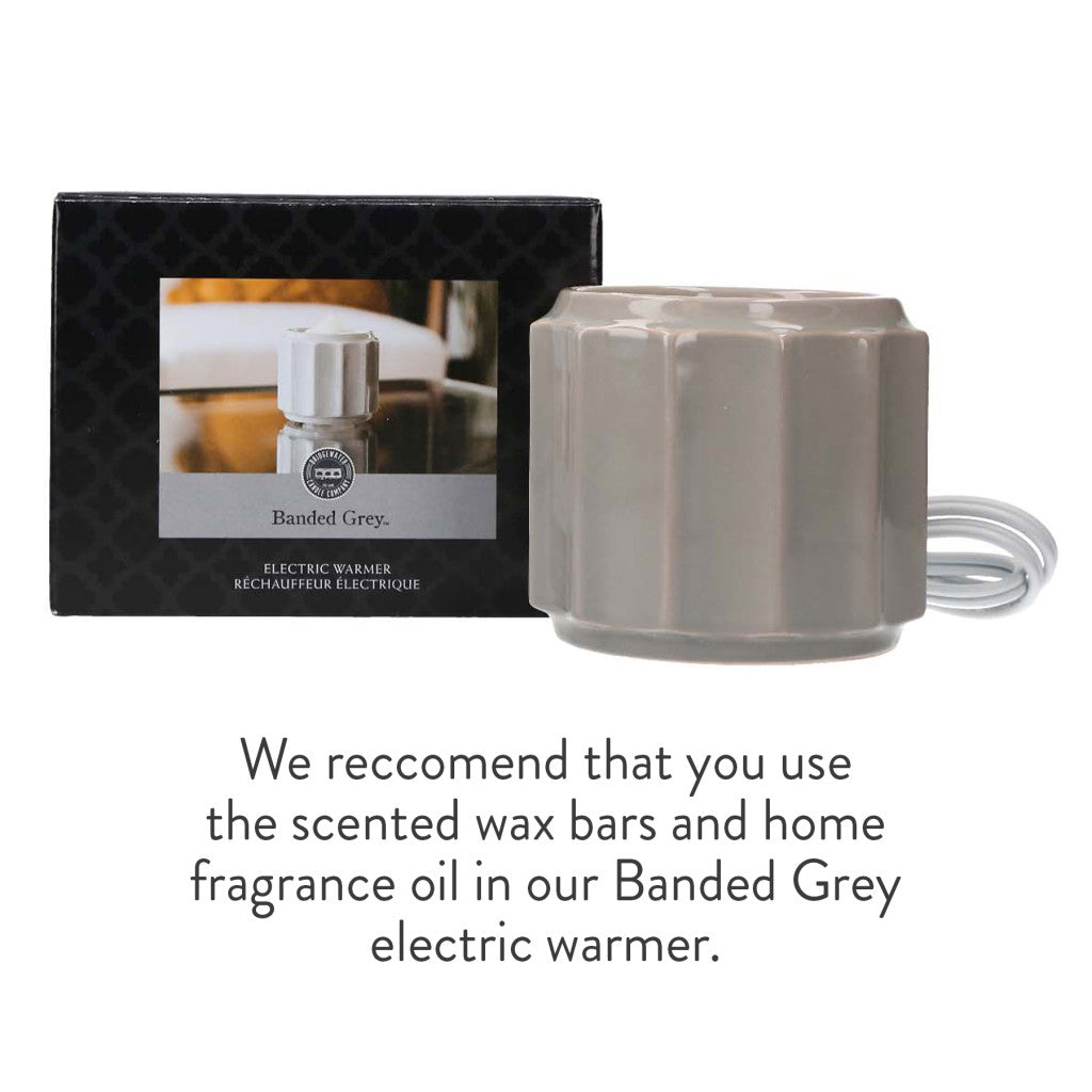 A gray, ridged electric warmer by Bridgewater Candle Company sits next to its box. Text below suggests pairing the Banded Grey electric warmer with scented wax bars, home fragrance oil, or the Welcome Home Flameless Bundle.