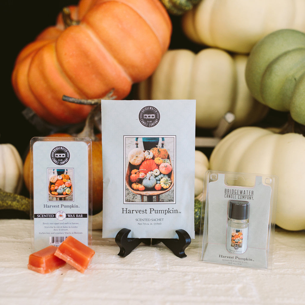 The Harvest Pumpkin Flameless Bundle by Bridgewater Candle Company includes a wax bar, sachet, and fragrance oil, each with pumpkin-themed designs. Displayed with orange and white pumpkins, it creates a cozy pumpkin spice vibe without flames.